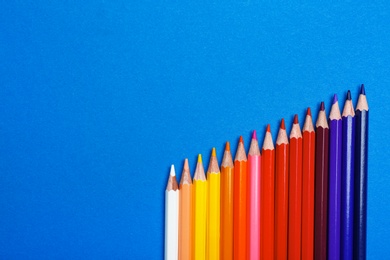 Photo of Color pencils on blue background, flat lay. Space for text