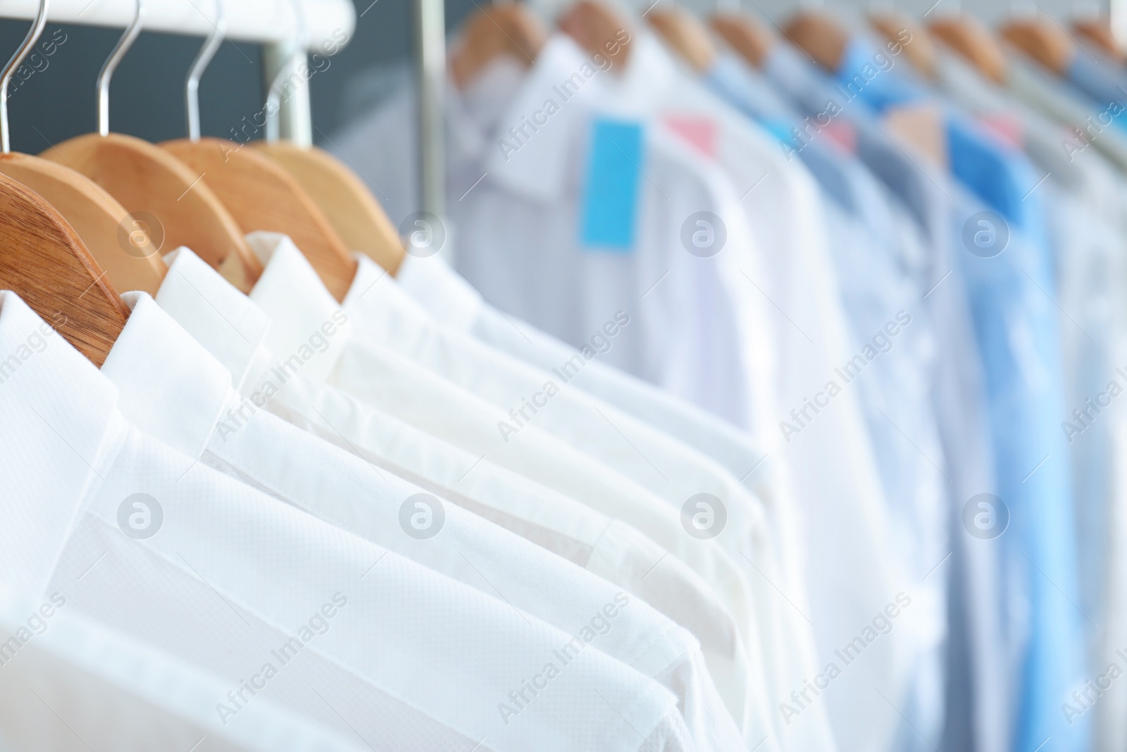 Photo of Clean clothes on hangers after dry-cleaning, closeup