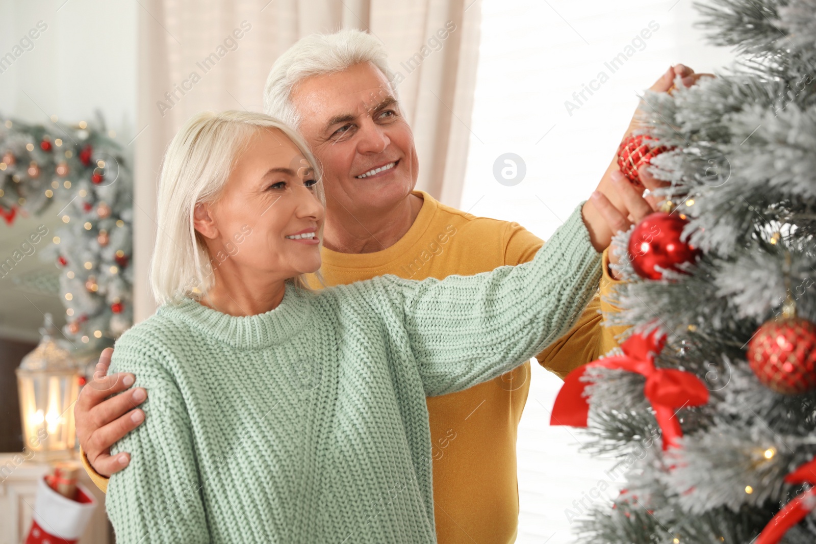 Photo of Happy mature couple decorating Christmas tree at home