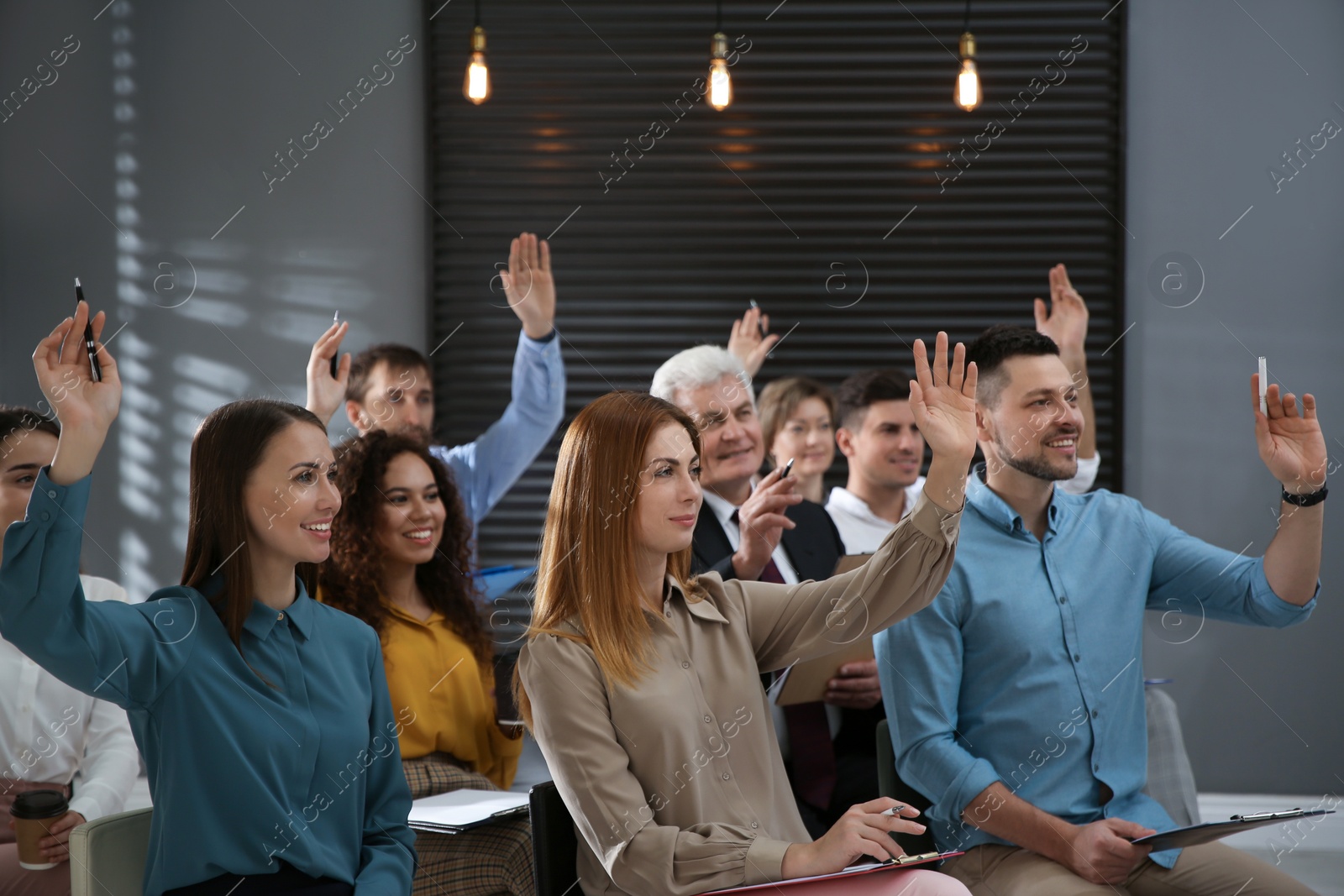 Photo of People raising hands to ask questions at seminar in office