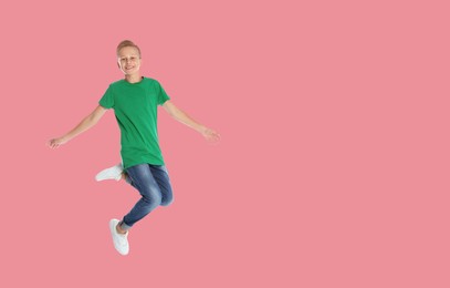 Image of Happy boy jumping on pink background, space for text