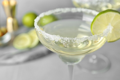 Glasses of lemon drop martini cocktail with lime slice on table against grey background, closeup