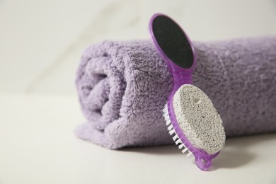 Photo of Pedicure tool with pumice stone and foot file near towel on white table, closeup