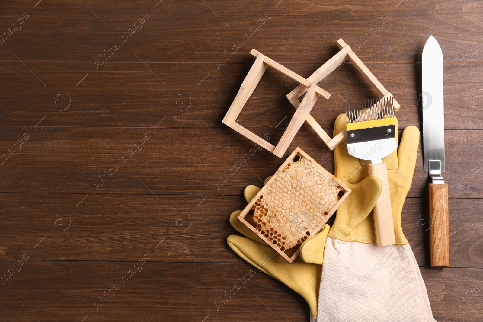 Photo of Honeycomb frames and beekeeping tools on wooden table, flat lay. Space for text