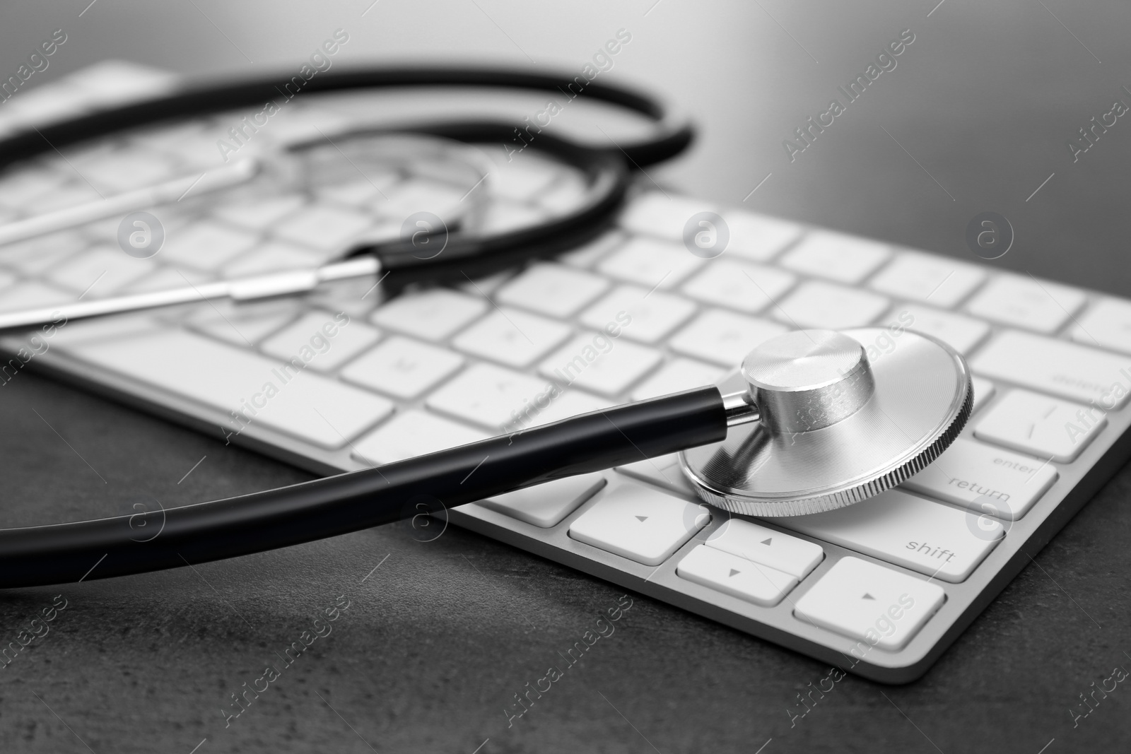 Photo of Modern keyboard and stethoscope on table. Technical support concept