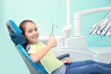 Photo of Happy little girl having dentist's appointment in modern clinic