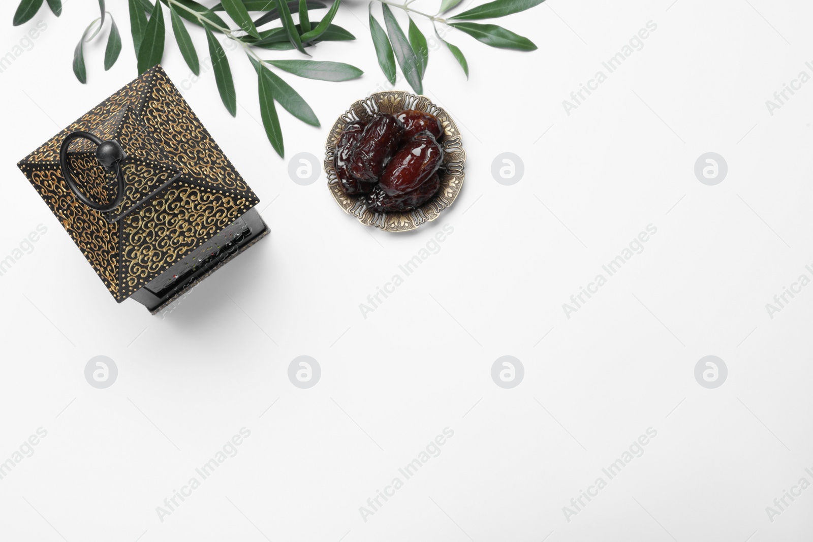 Photo of Arabic lantern, dates and green branches on white background, top view