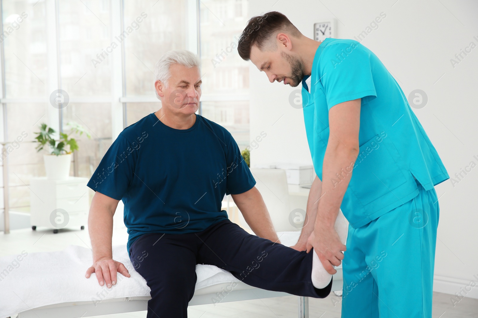 Photo of Young physiotherapist working with senior patient in clinic