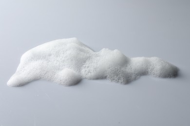 Photo of Drop of fluffy soap foam on light grey background