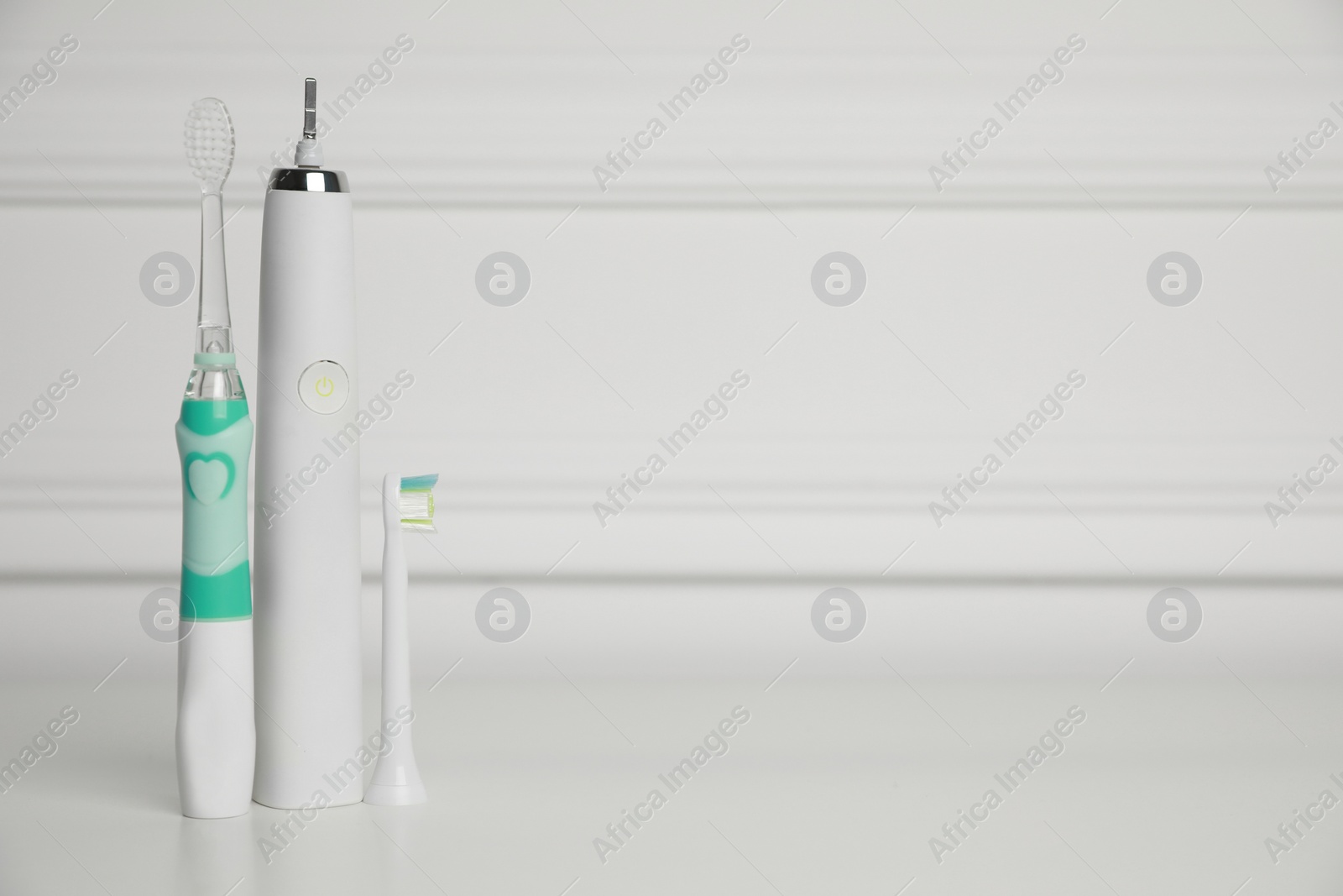 Photo of Electric toothbrushes on white background, space for text