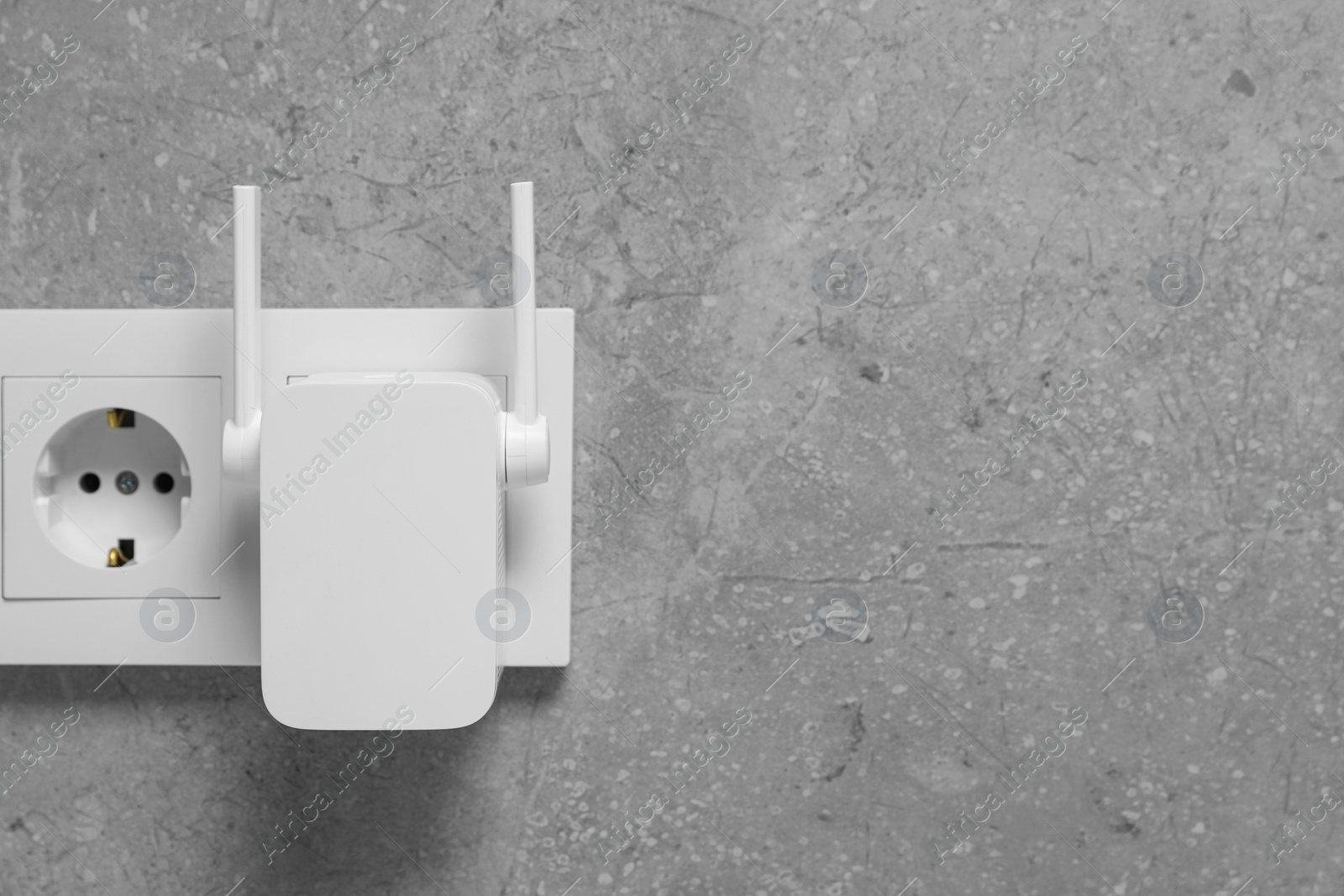 Photo of Wireless Wi-Fi repeater on light grey wall, space for text