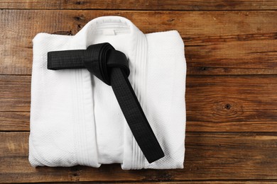 Photo of Black karate belt and white kimono on wooden background, top view