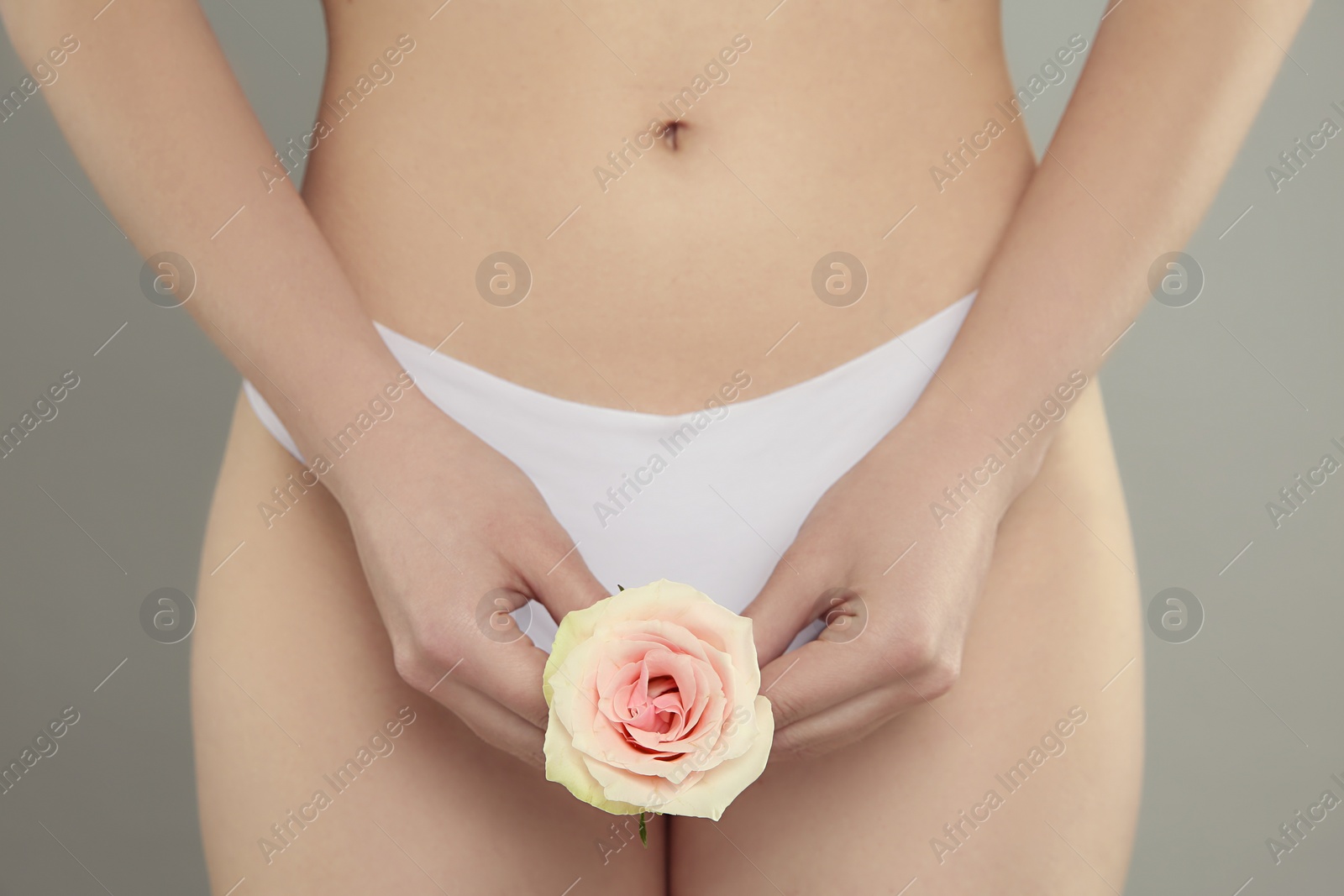 Photo of Gynecology. Woman in underwear with rose flower on grey background, closeup