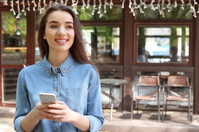 Photo of Young woman using mobile phone outdoors