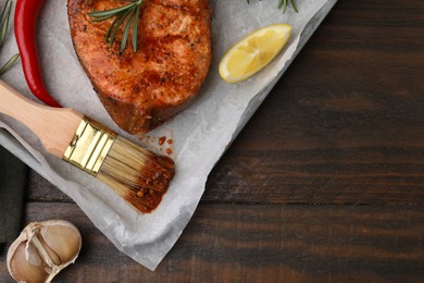 Photo of Fresh marinade, fish, brush and other products on wooden table, flat lay. Space for text