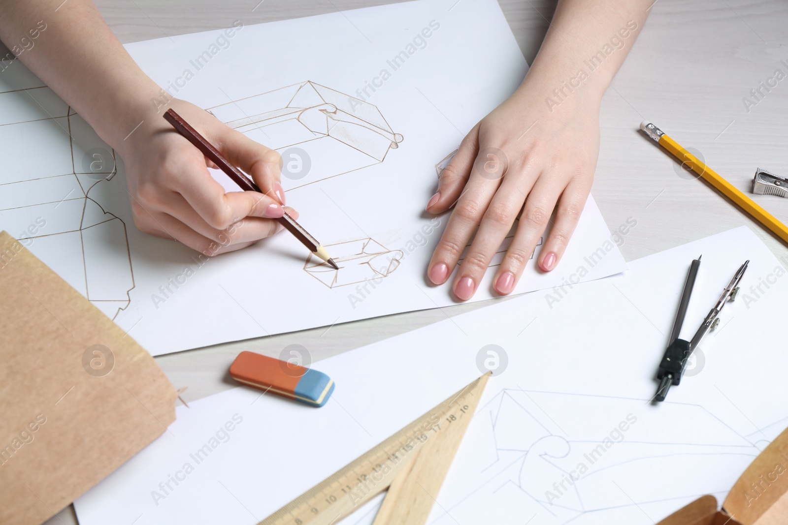 Photo of Woman creating packaging design at light wooden table, closeup