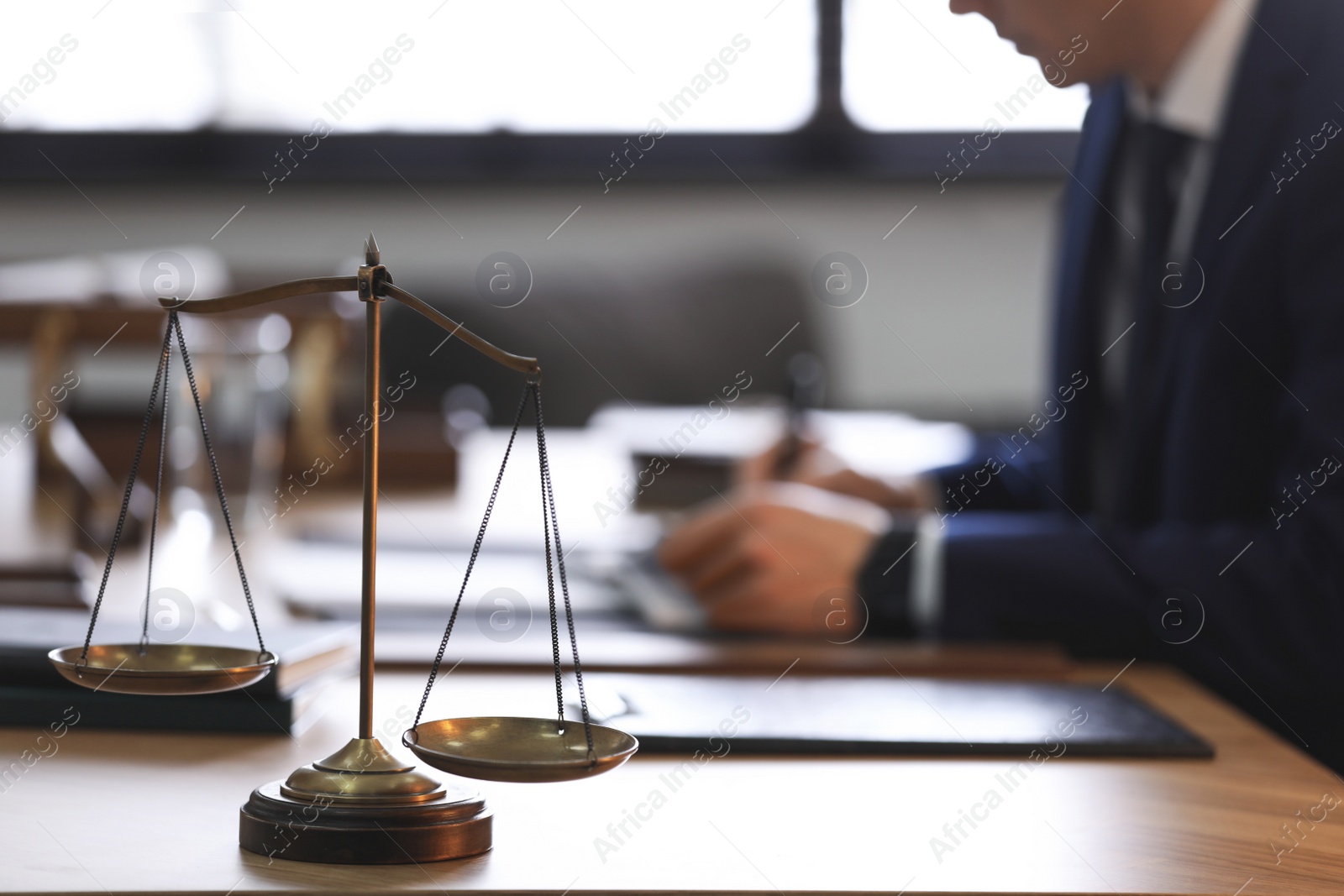 Photo of Scales of justice and blurred lawyer on background