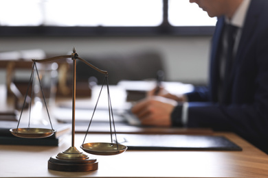 Photo of Scales of justice and blurred lawyer on background