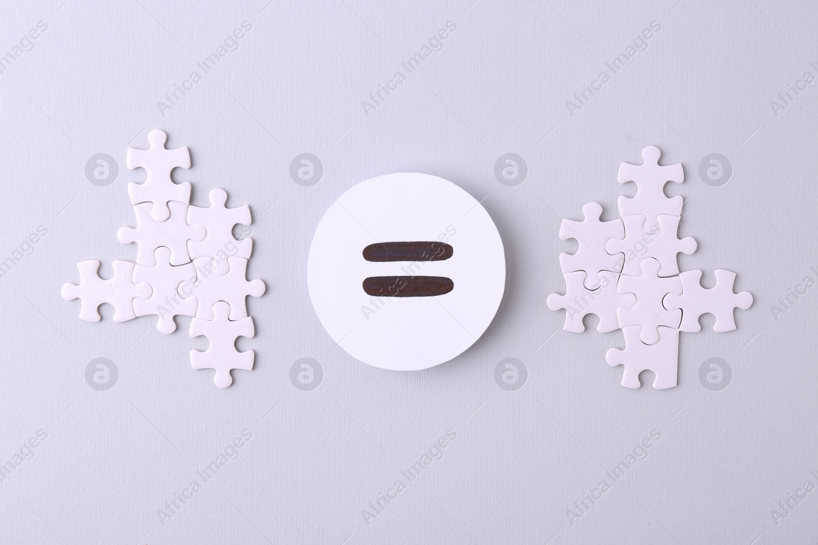 Photo of Puzzle pieces and equals sign on light background, flat lay