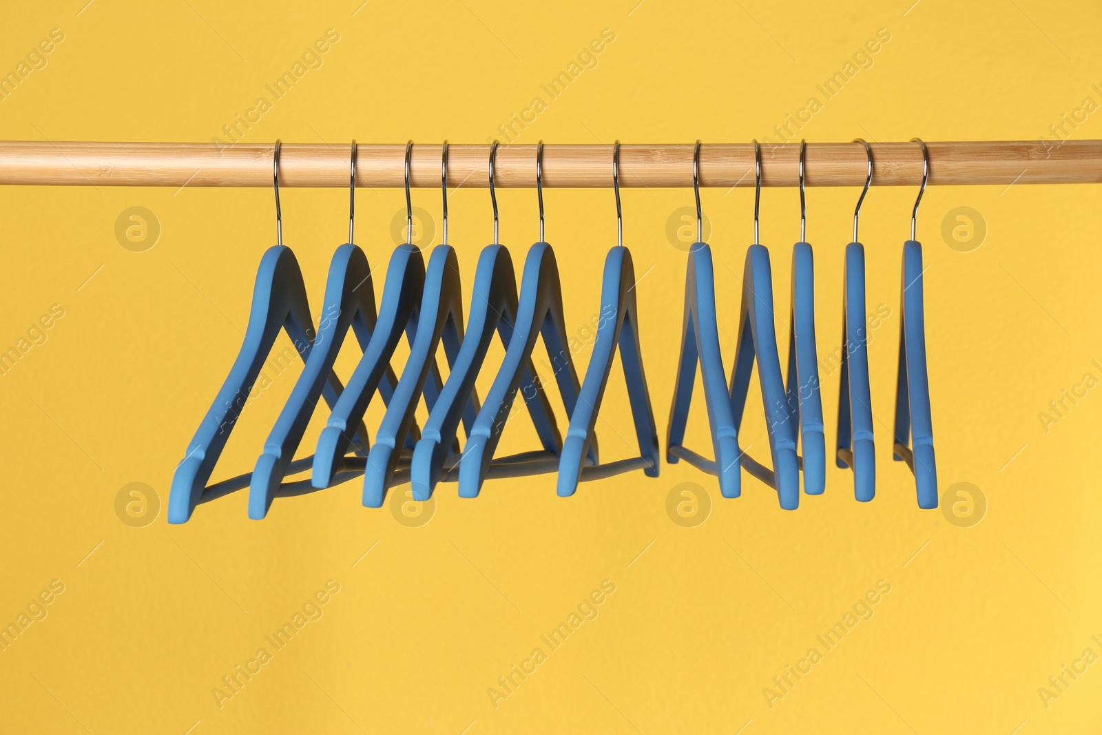 Photo of Wooden rack with clothes hangers on color background