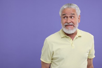Portrait of embarrassed senior man on purple background. Space for text