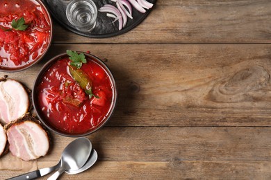 Photo of Stylish brown clay bowls with Ukrainian borsch served on wooden table, flat lay. Space for text