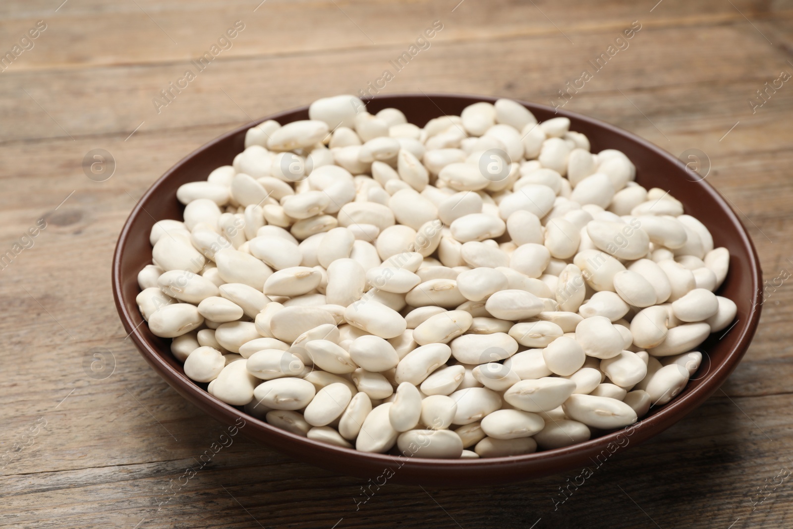 Photo of Raw white beans on wooden table, closeup