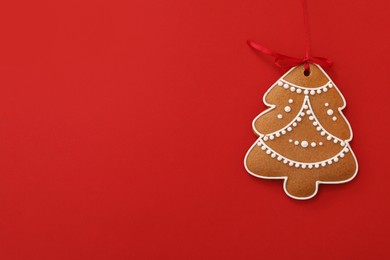 Photo of Christmas tree shaped cookie on red background, top view. Space for text