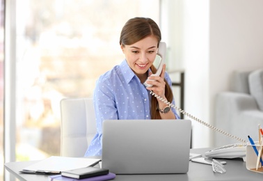 Young woman talking on phone at workplace