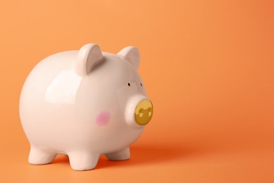 Photo of Ceramic piggy bank on orange background. Space for text