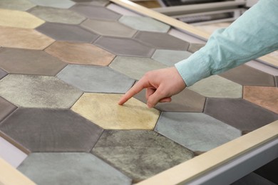 Photo of Man choosing tile among different samples in store, closeup