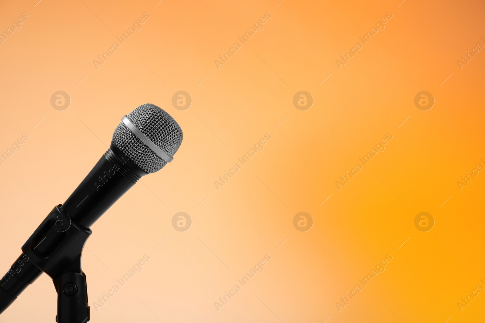 Photo of Modern microphone on stand against color background. Space for text