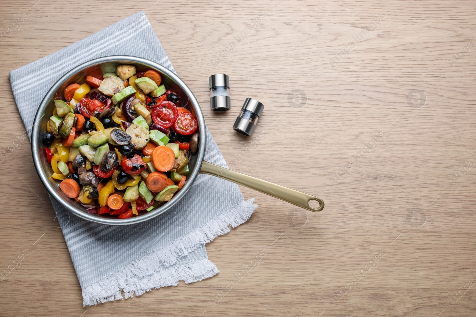 Photo of Frying pan with tasty cooked vegetables and mushrooms on wooden table, flat lay. Space for text