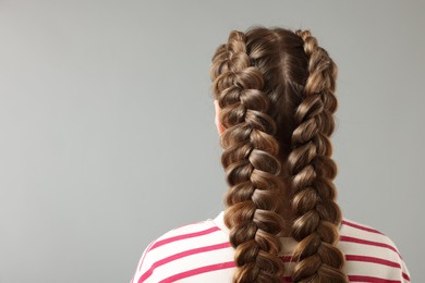 Photo of Woman with braided hair on grey background, back view. Space for text