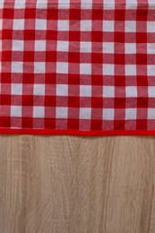 Photo of Checkered picnic cloth on wooden table, top view. Space for text