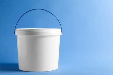 Photo of One plastic bucket with lid on light blue background. Space for text