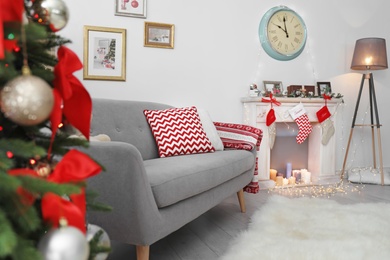 Photo of Comfortable sofa near decorated Christmas tree and fireplace in living room