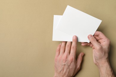 Photo of Man holding flyers on light brown background, top view. Mockup for design