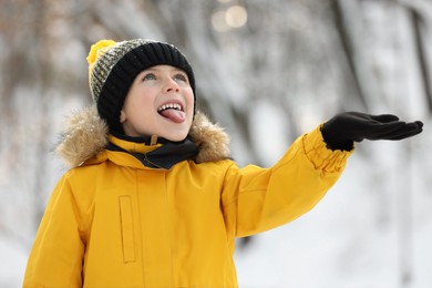 Photo of Cute little boy having fun in snowy park on winter day