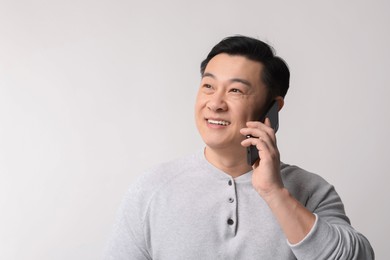 Photo of Portrait of happy man talking by smartphone on light background. Space for text