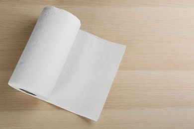 Photo of Roll of paper tissues on wooden table, top view. Space for text