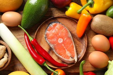 Photo of Healthy meal. Different vegetables and raw salmon on wooden table, flat lay