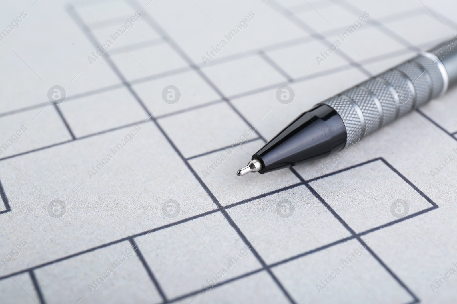 Photo of Pen on blank crossword, closeup. Space for text