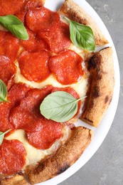 Tasty pepperoni pizza with basil on grey table, top view