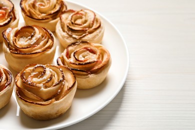 Freshly baked apple roses on white wooden table, space for text. Beautiful dessert