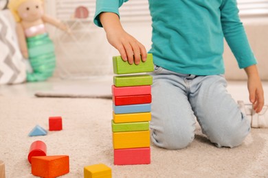 Photo of Cute little girl playing with colorful building blocks at home, closeup