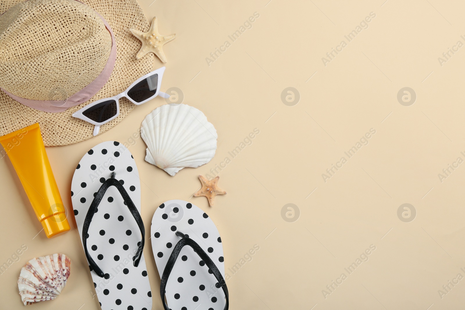 Photo of Flat lay composition with flip flops and beach accessories on beige background. Space for text