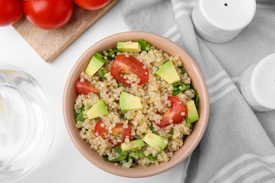 Photo of Delicious quinoa salad with tomatoes, avocado and parsley served on white table, flat lay
