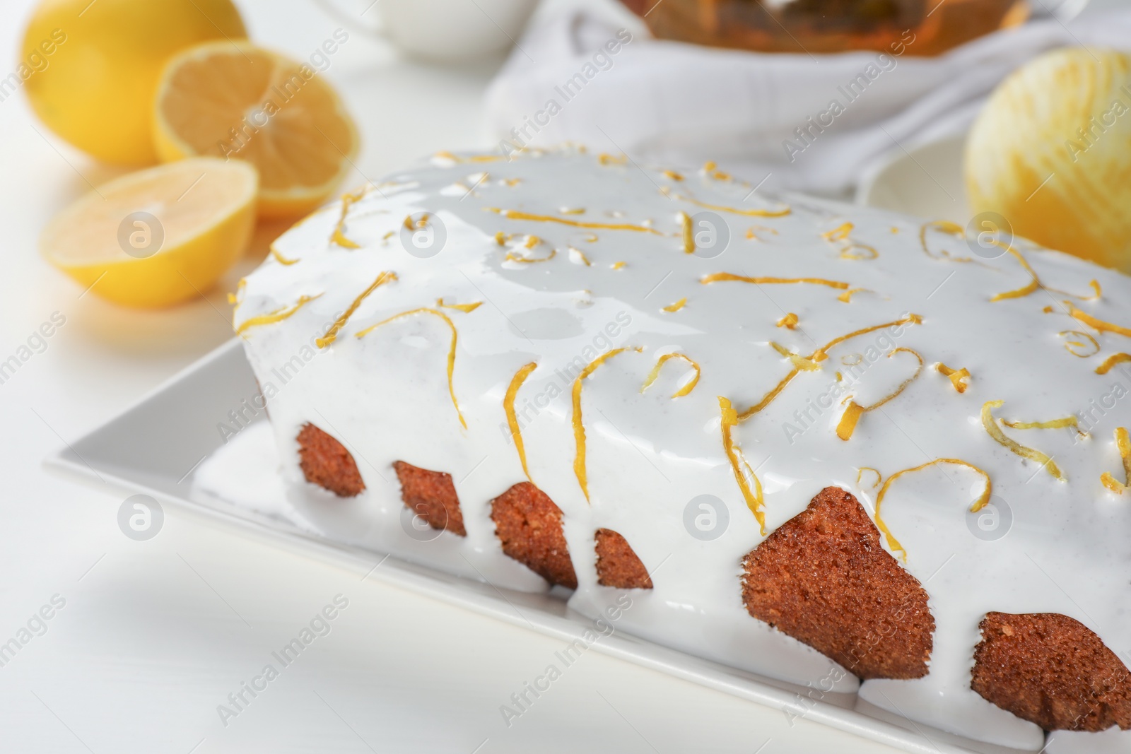 Photo of Tasty lemon cake with glaze on white table, closeup