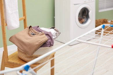 Photo of Laundry basket filled with clothes on chair in bathroom. Space for text